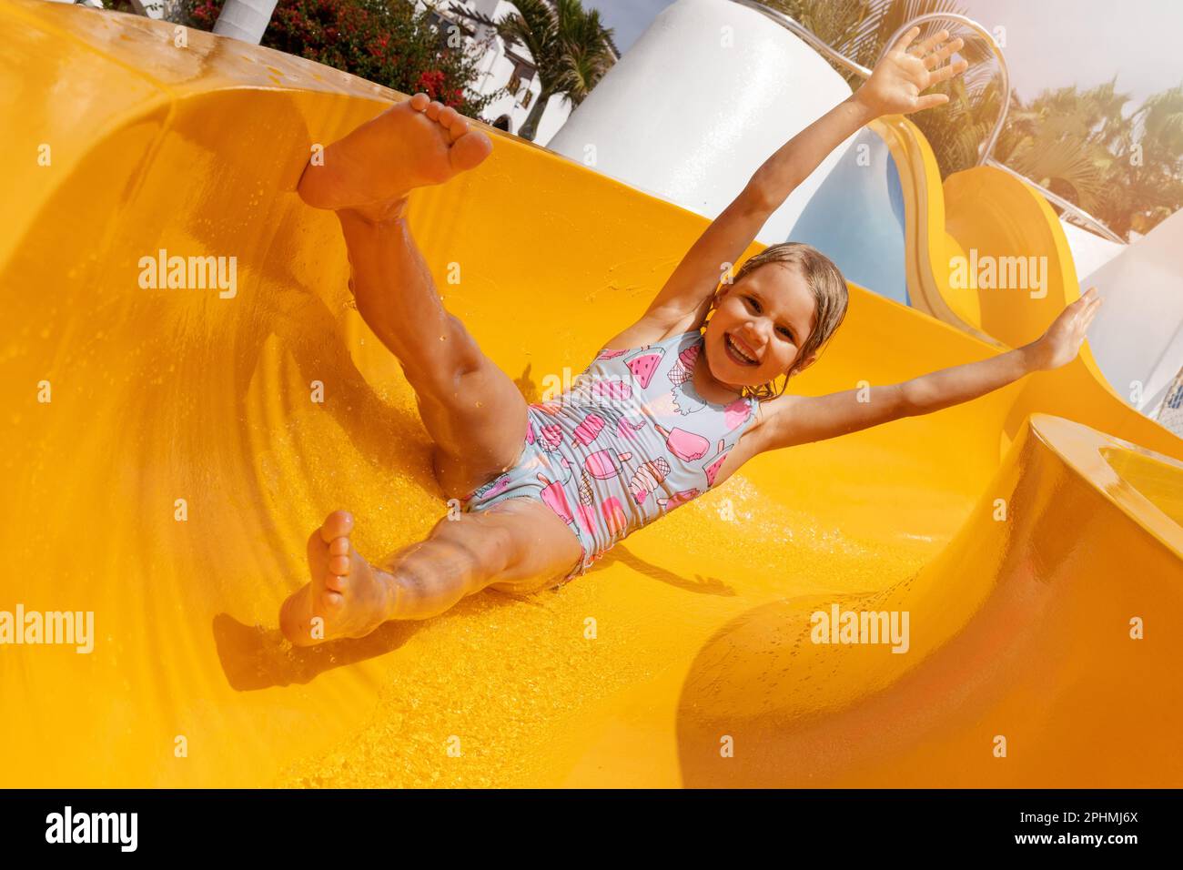 Glückliches Kind mit Spaß auf der Rutsche im Wasserpark im Freien. Sommerferien Stockfoto