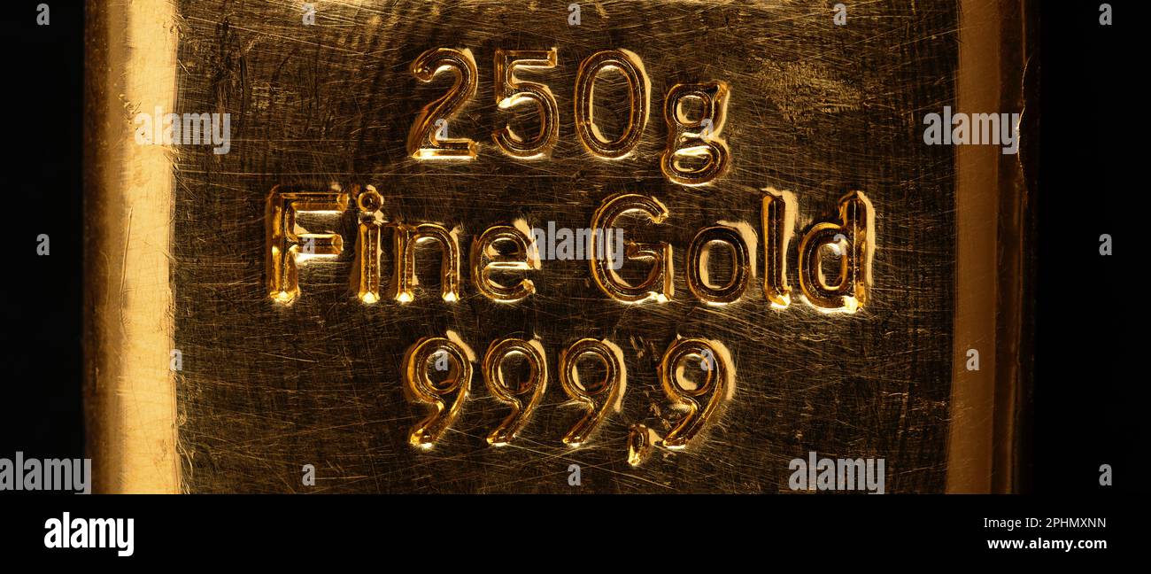 Geprägte Schrift auf einem goldenen Balken, auch bekannt als Goldbarren. Raffiniertes metallisches Gold, hergestellt durch Gießen von geschmolzenem Metall in eine stabförmige Form. Stockfoto