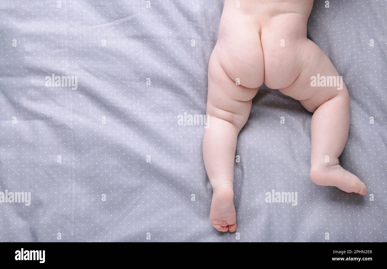 Kleine süße Babybeine auf grauem Bett mit Kopierbereich Stockfoto