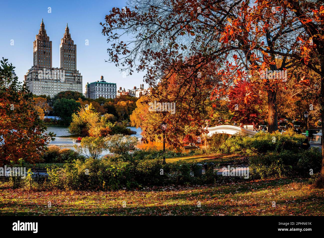 USA, New York, Manhattan, Central Park, Blick auf den See und die Bow Bridge bis zum San Remo Apartments Gebäude im Herbst Stockfoto