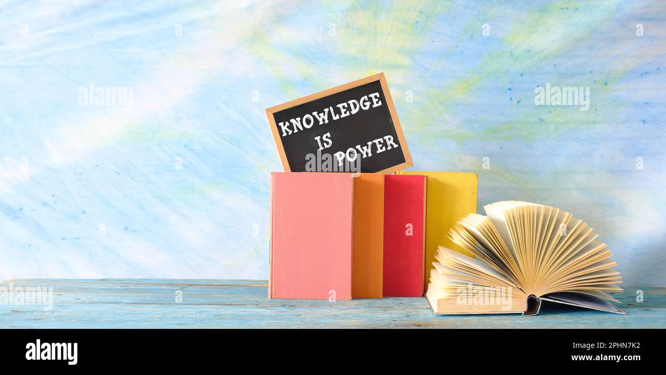 Bildung, Lernen, Wissenskonzept, Bücher, offenes Buch und Tafel mit dem Slogan Wissen ist Macht. Stockfoto