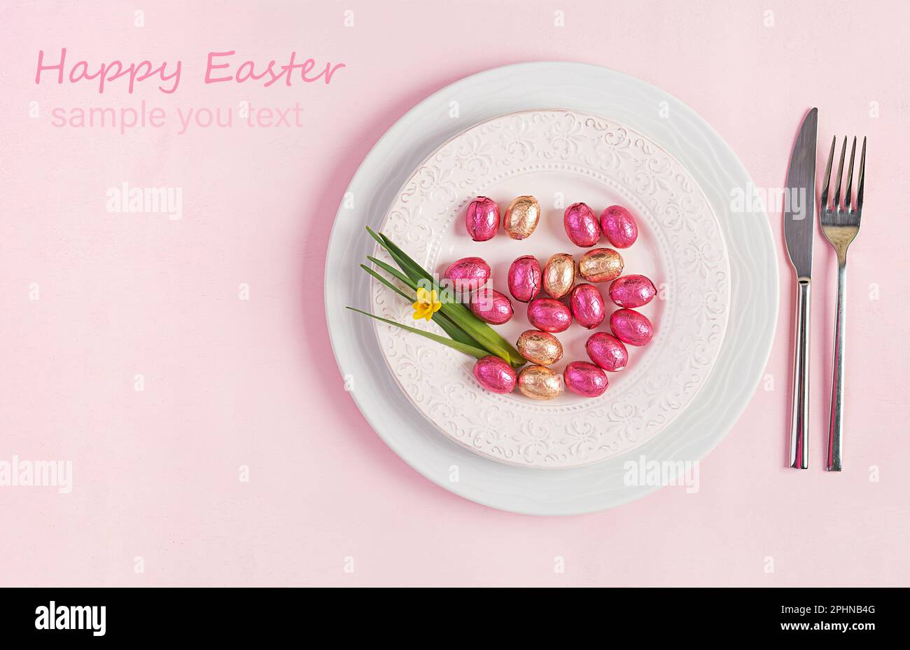 Frohe Ostern. Tischdecken für Osterferien. Ostereier, Blumen und Besteck auf pinkfarbenem Hintergrund. Draufsicht, flach liegend Stockfoto