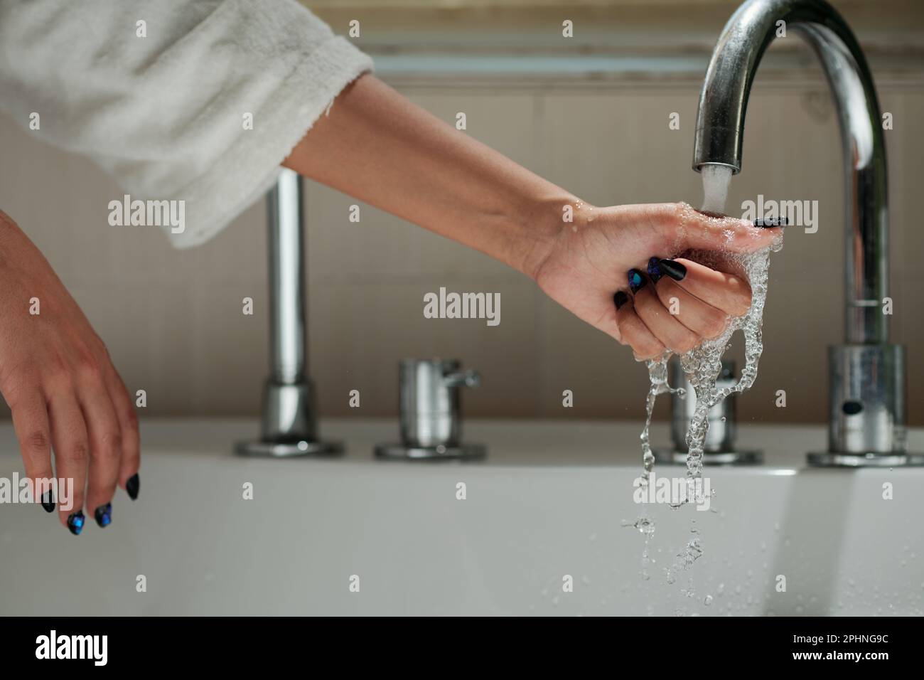 Hand einer Frau, die beim Befüllen der Badewanne Leitungswasser berührt Stockfoto
