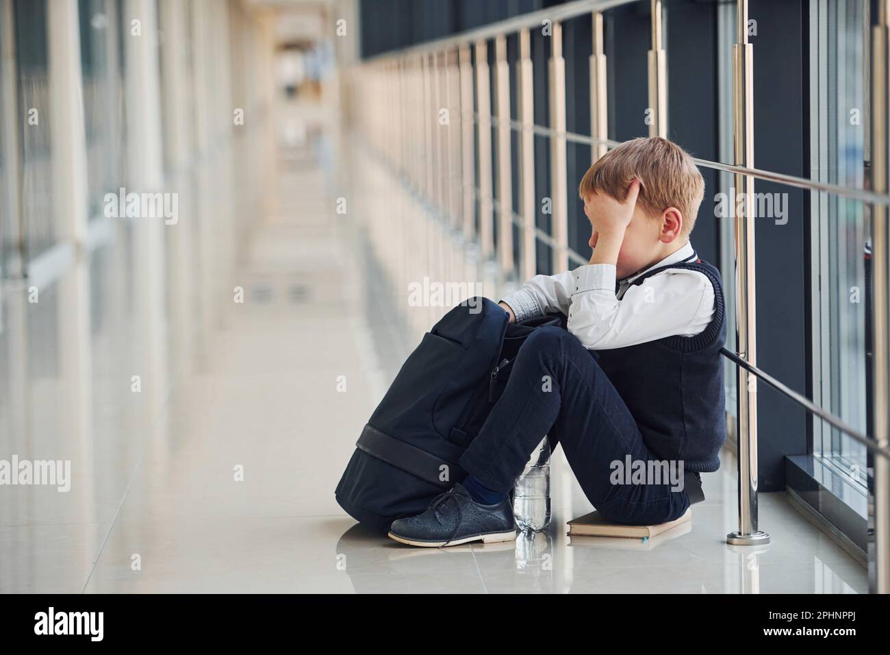 Ein Junge in Uniform, der in der Schule allein sitzt und traurig ist