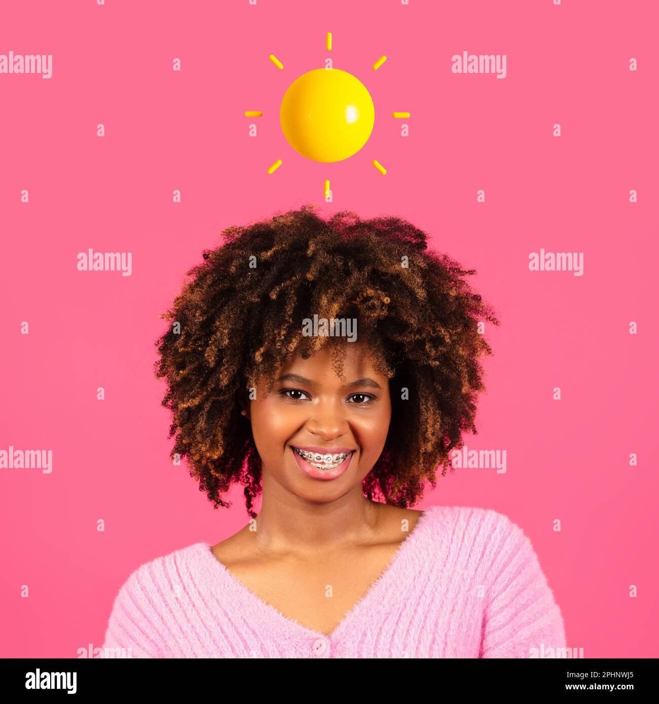 Lächelnde junge afroamerikanische lockige Frau mit abstrakter Sonne über dem Kopf Stockfoto