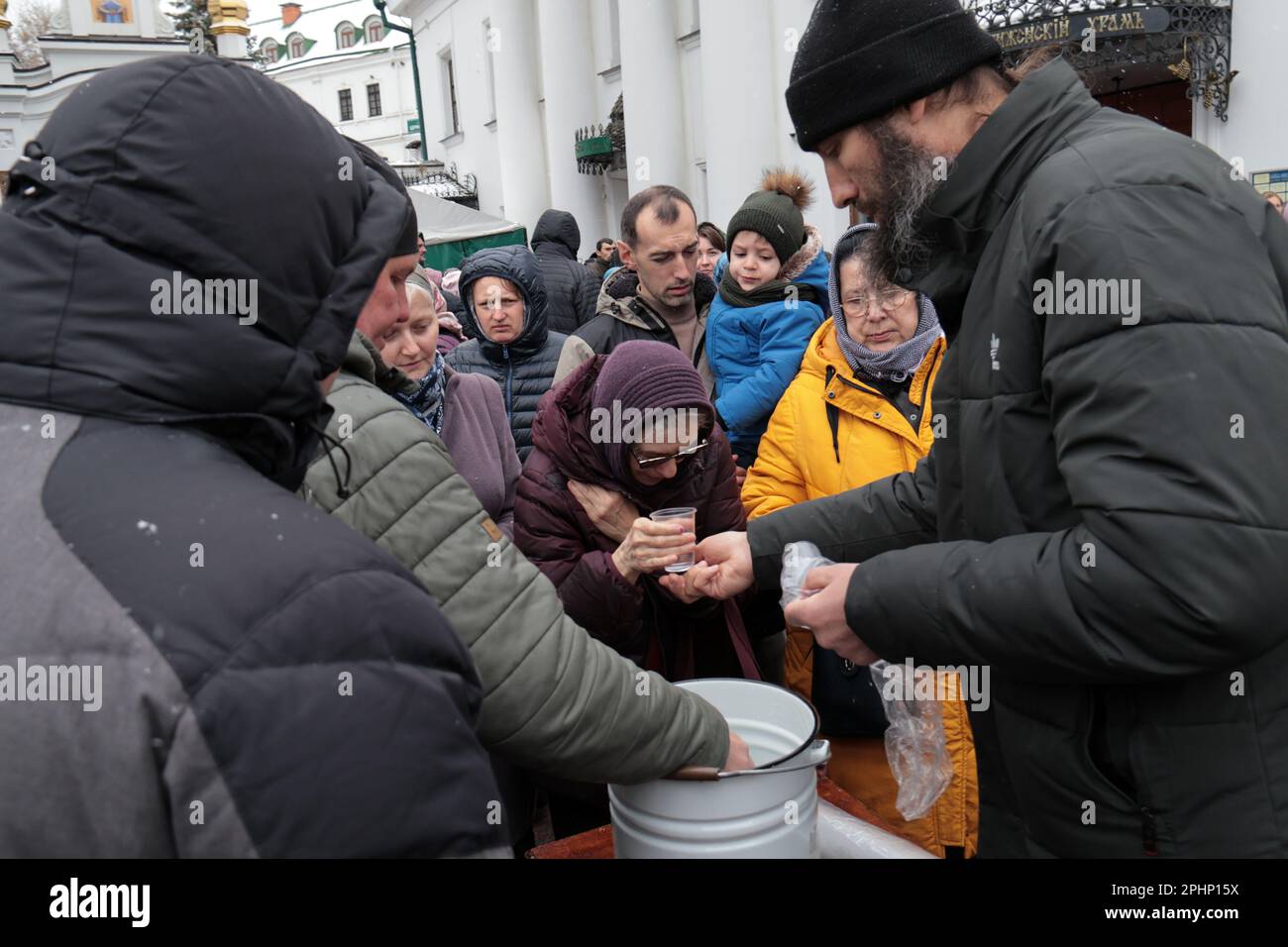 KIEW, UKRAINE - 29. MÄRZ 2023 - Gläubige akzeptieren Tassen Wasser während eines morgendlichen Gottesdienstes vor der Kirche des Heiligen Kreuzes als Kiew Pechersk Lavra Natio Stockfoto