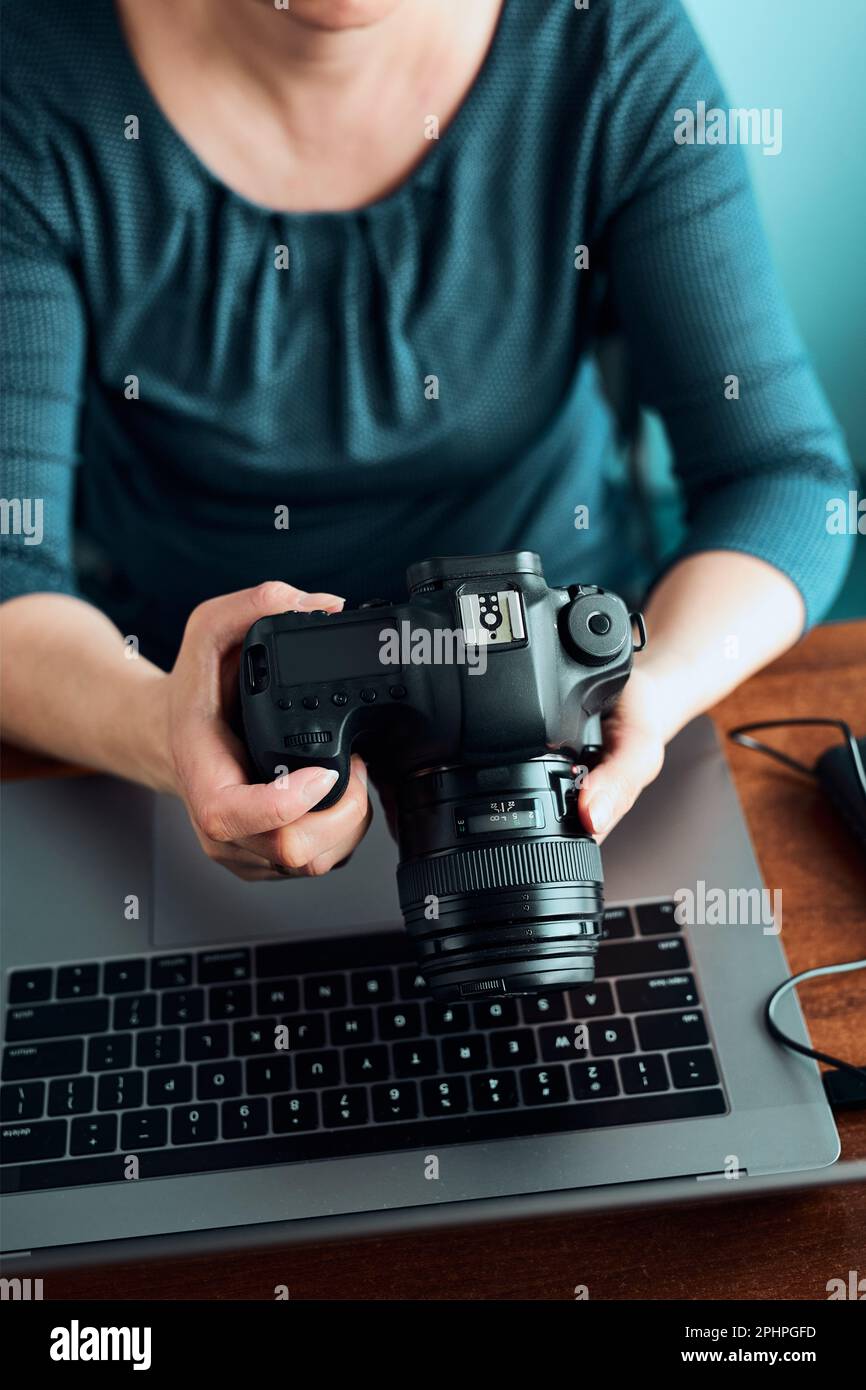 Fotografin arbeitet an Fotos auf Laptop und Kamera. Frau Bearbeitung Retusche durchsuchen Fotos arbeiten als freiberufliche am Schreibtisch sitzen Stockfoto