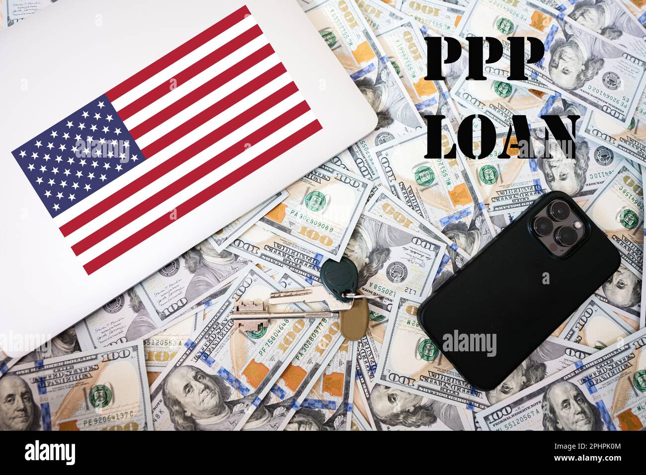 ÖPP-Darlehen. Konzept des Programms zum Schutz des Gehaltsschecks. US-Flagge, Dollargeld mit Schlüsseln, Laptop- und Telefonhintergrund. Stockfoto