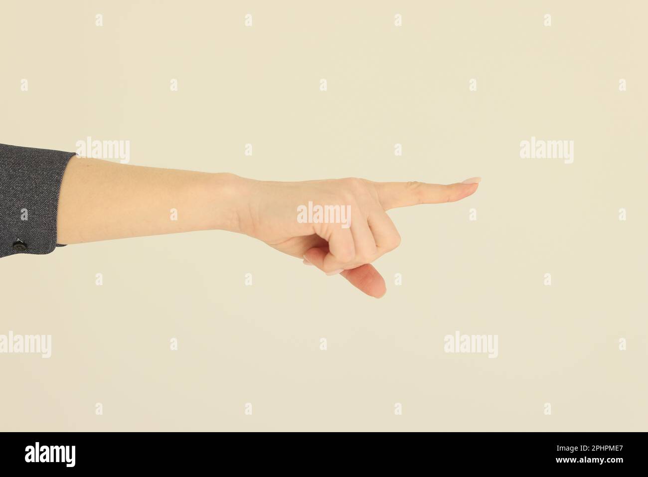Die Hand einer Frau zeigt mit dem Zeigefinger auf einen beigen Hintergrund Stockfoto