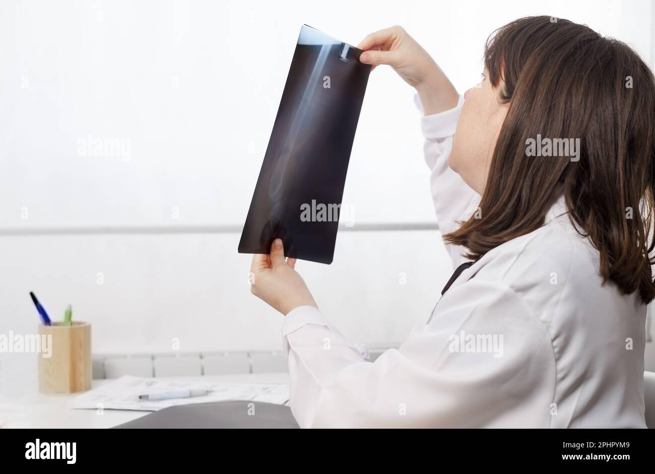 Eine junge Ärztin, die die Röntgenaufnahmen eines Patienten untersucht Stockfoto