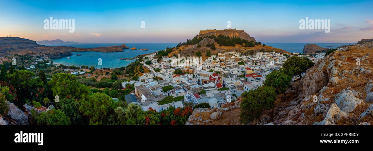 Blick auf die Akropolis von Lindos bei Sonnenuntergang mit Blick auf traditionelle weiße Häuser auf der Insel Rhodos, Griechenland. Stockfoto