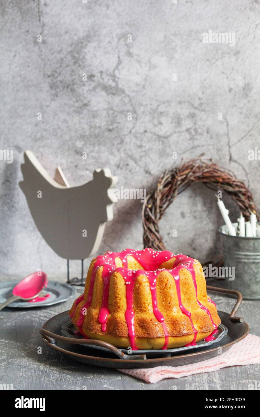 Orangefarbener Vanillekuchen mit pinkfarbenem Glasur, Osterdekor. Stockfoto