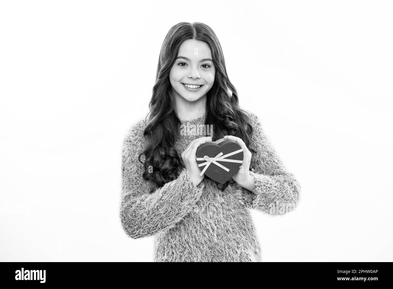 Geschenkbox mit Herz. Ein weißes Teenager-Mädchen hat ein Geschenk auf weißem, isoliertem Studiohintergrund. Teenager, die Geburtstag feiert, ein Geschenk in der Hand hat Stockfoto