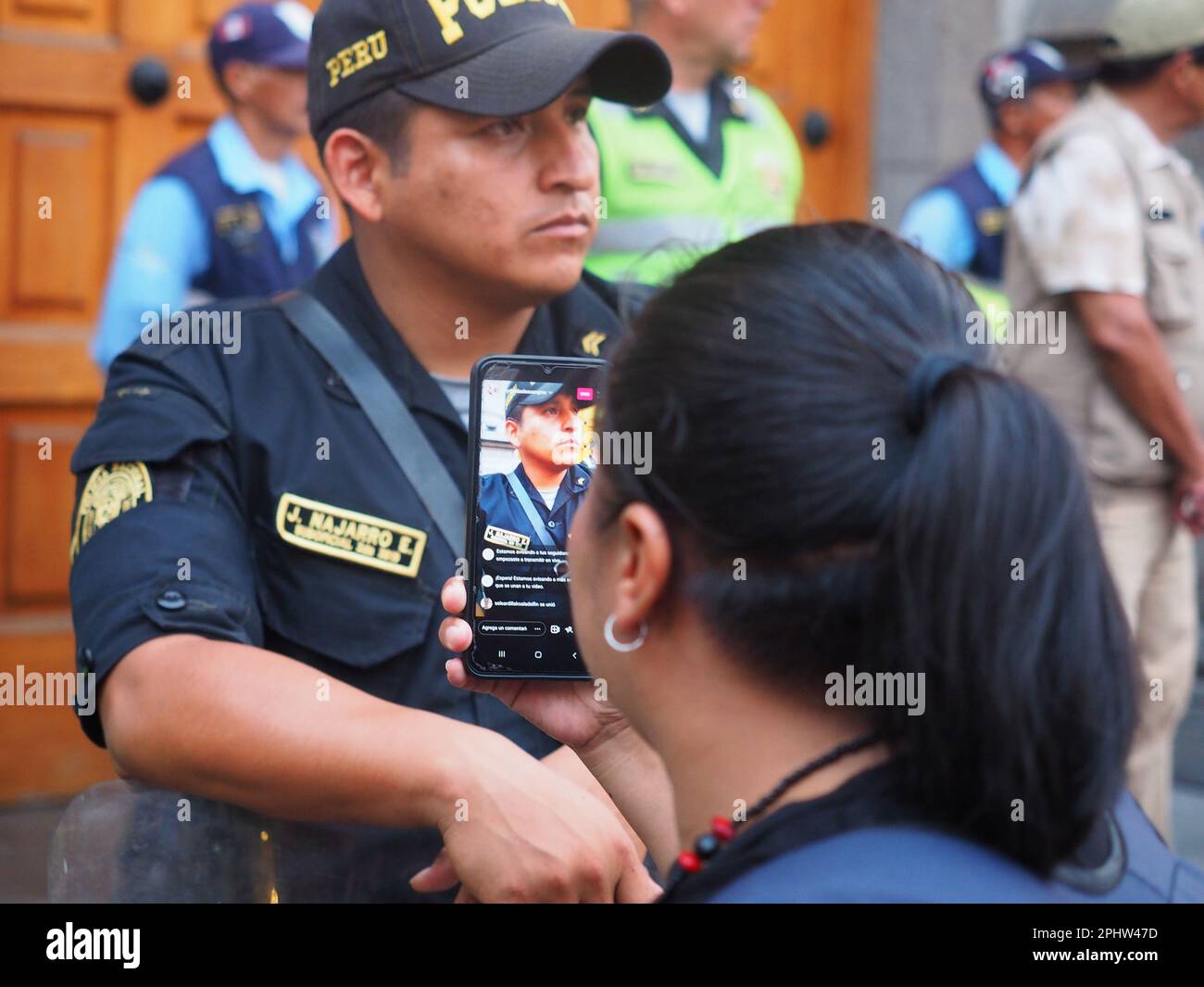 Peru, 29/03/2023, Eine Demonstrantin, die Fotos von der Polizei mit ihrem Handy macht, während Dutzende vor der Gemeinde Miraflores in Lima einen Protest wegen der kürzlichen Schließung des Ortes der Erinnerung halten, Toleranz und soziale Eingliederung (LUM) einige Stunden bevor Amnesty International den Ort nutzen sollte, um seinen Jahresbericht vorzulegen, in dem die Menschenrechtslage in Peru als "bedauerlich" beschrieben wird. Der Ort der Erinnerung ist ein Museum, das vom peruanischen Kulturministerium verwaltet wird und den Opfern des peruanischen internen Konflikts der 1980er und 1990er Jahre gewidmet ist. Stockfoto