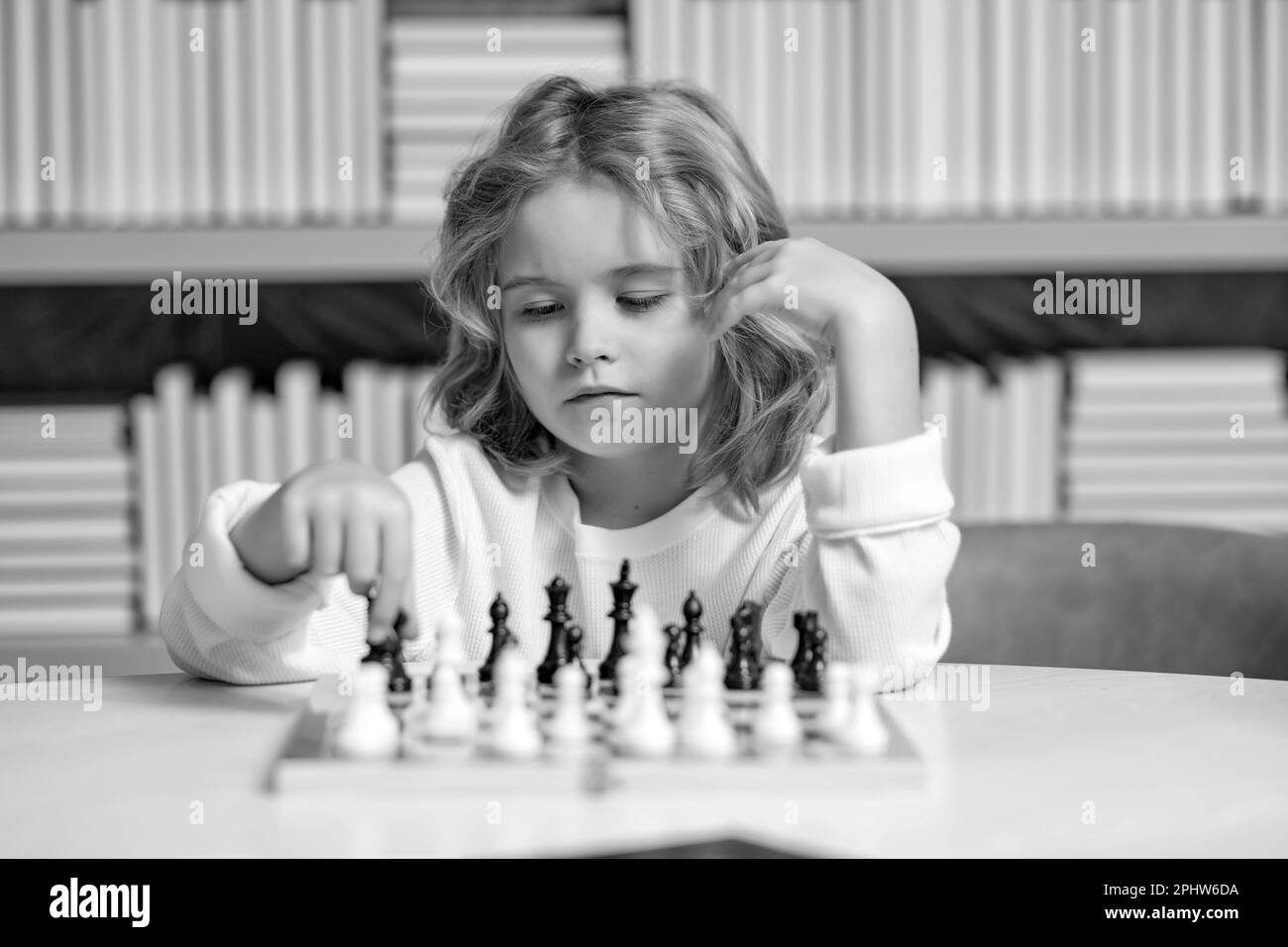 Frühe Entwicklung. Der Junge denkt an Schach. Das Konzept des Lernens und des heranwachsenden Kindes. Schach, Erfolg und Sieg. Stockfoto