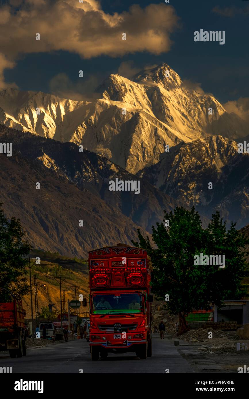 Landschaft mit Schneebirgen und Straße mit bunten Lastwagen, wunderschön dekorierte pakistanische Lastwagen auf der Karakorum Autobahn in gilgit baltistan Stockfoto