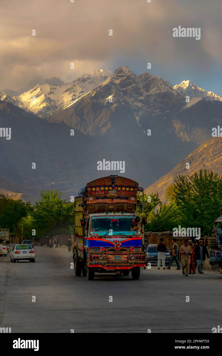 Landschaft mit Schneebirgen und Straße mit bunten Lastwagen, wunderschön dekorierte pakistanische Lastwagen auf der Karakorum Autobahn in gilgit baltistan Stockfoto