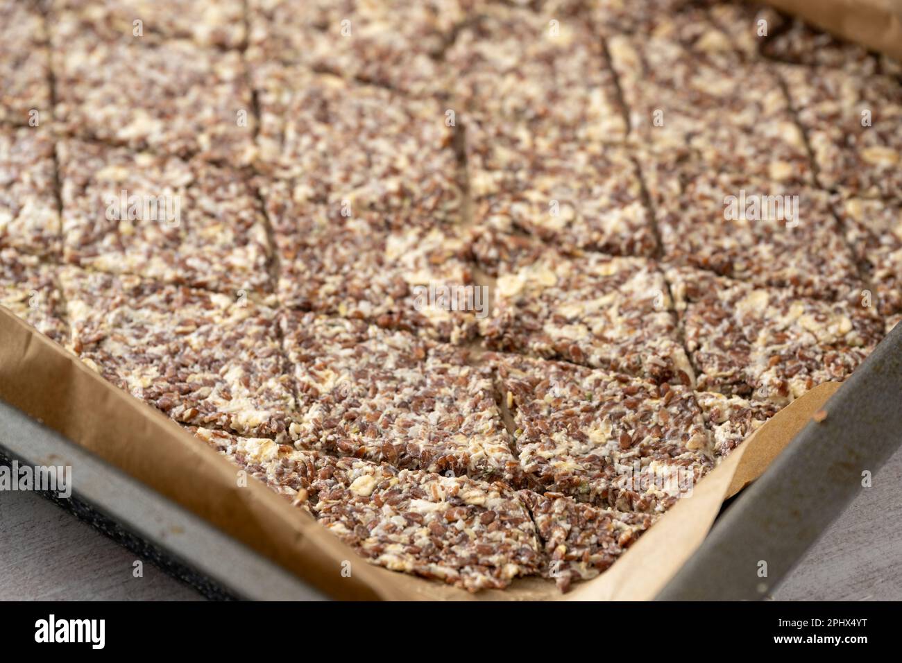 Backblech mit Teig aus Leinsamen, Haferflocken und Käse, in Rhombs geschnitten, um gesunde knusprige Backwaren zu machen, Platz zum Kopieren, ausgewählter Fokus, eng Stockfoto