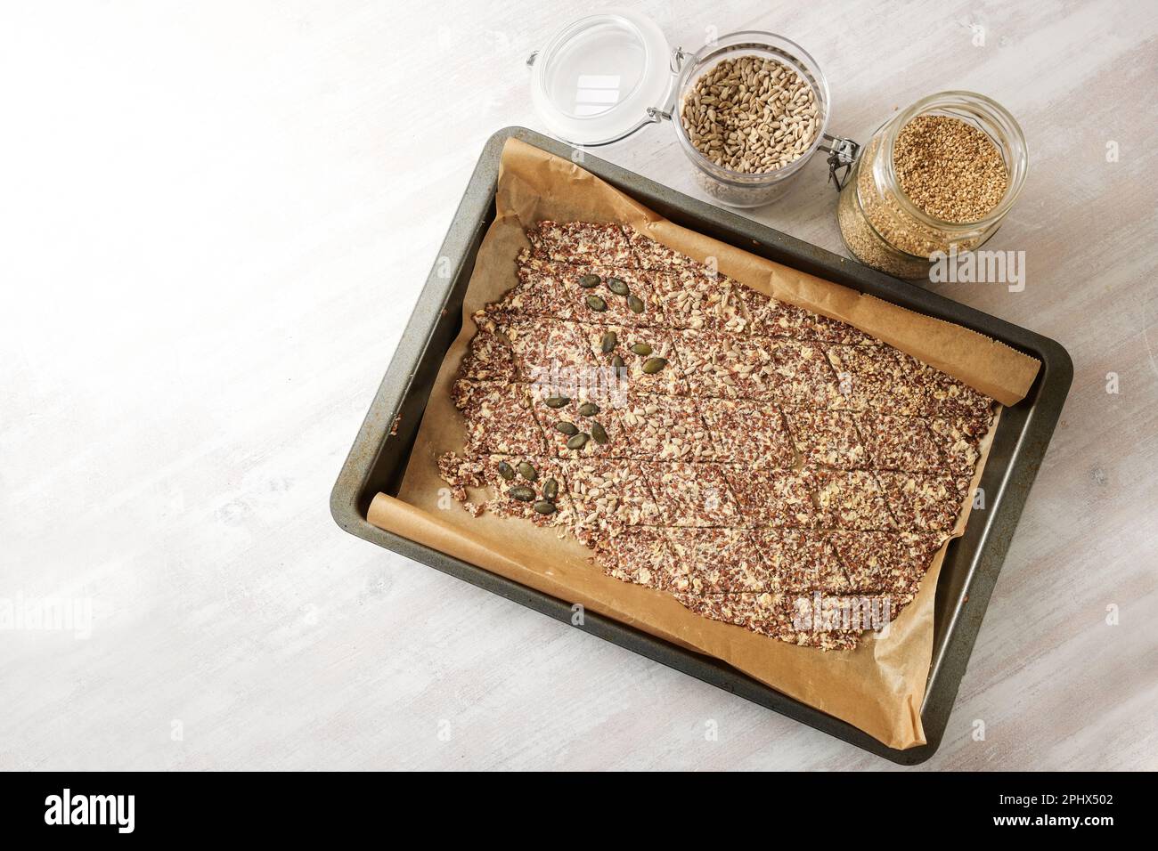 Backblech mit Teig aus Leinsamen und Haferflocken, geschnitten in Rhombs und garniert mit verschiedenen Samen für gesunde Backwaren, Kopierbereich, Top iew from Stockfoto