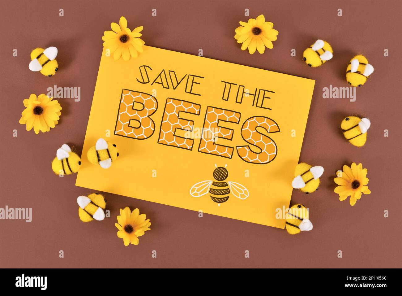 Das Schild „Rettet die Bienen“ umgeben von Filzbienen und gelben Blumen Stockfoto