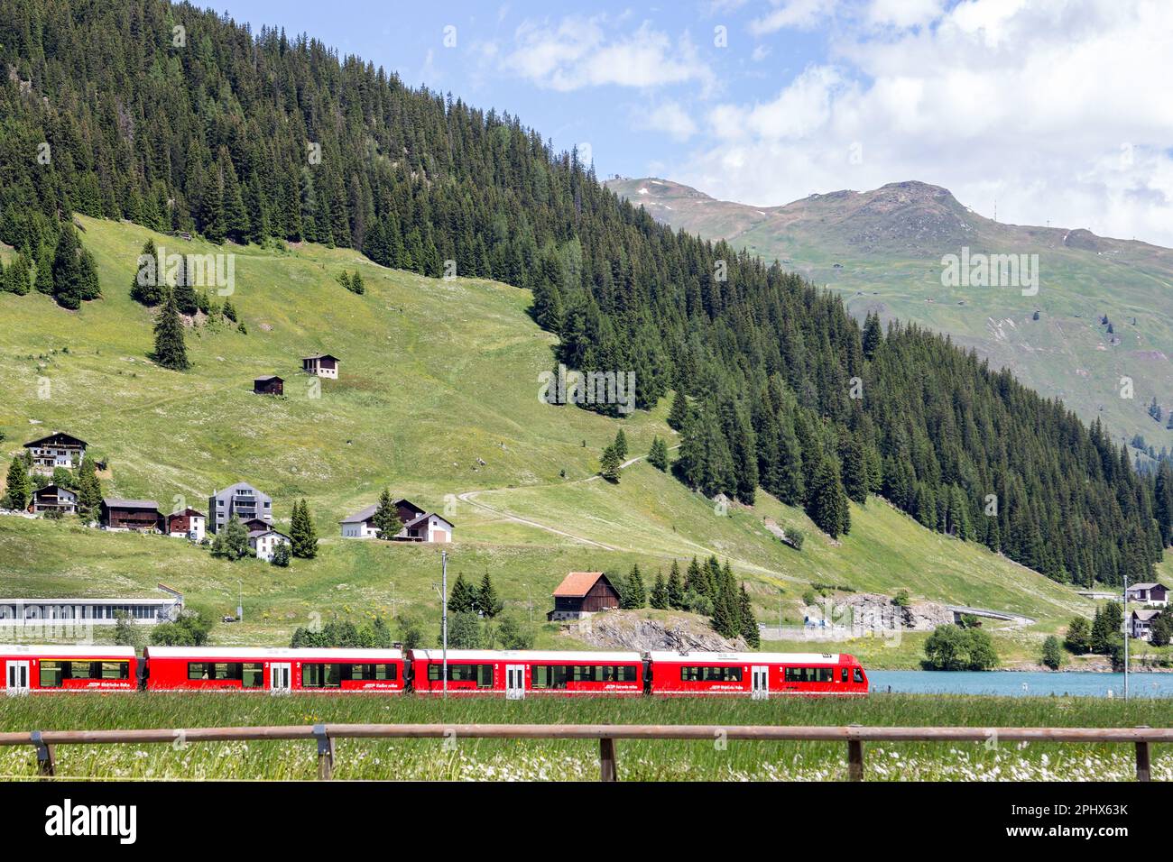 Davos, Schweiz - Juni 24. 2021: Ein roter Passagier-Expresszug von Rhatian Railway Company überquert den wunderschönen Davos-See, Grison, SWI Stockfoto