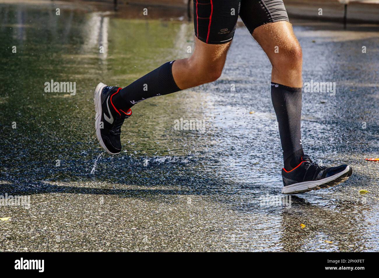 Männlicher Läufer, der sich auf der Wasserstraße beim Marathonrennen, Schuhen, Kompressionssocken und Strumpfhosen der französischen Laufmarke Kalenji bewegt Stockfoto