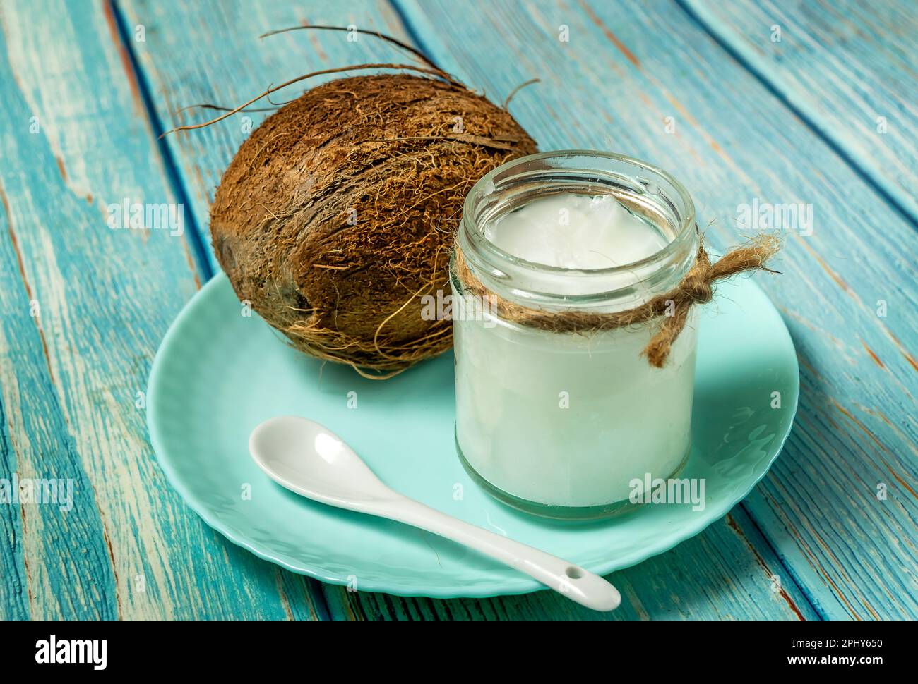 Kokosöl und frische Kokosnüsse auf altem Holztisch Stockfoto