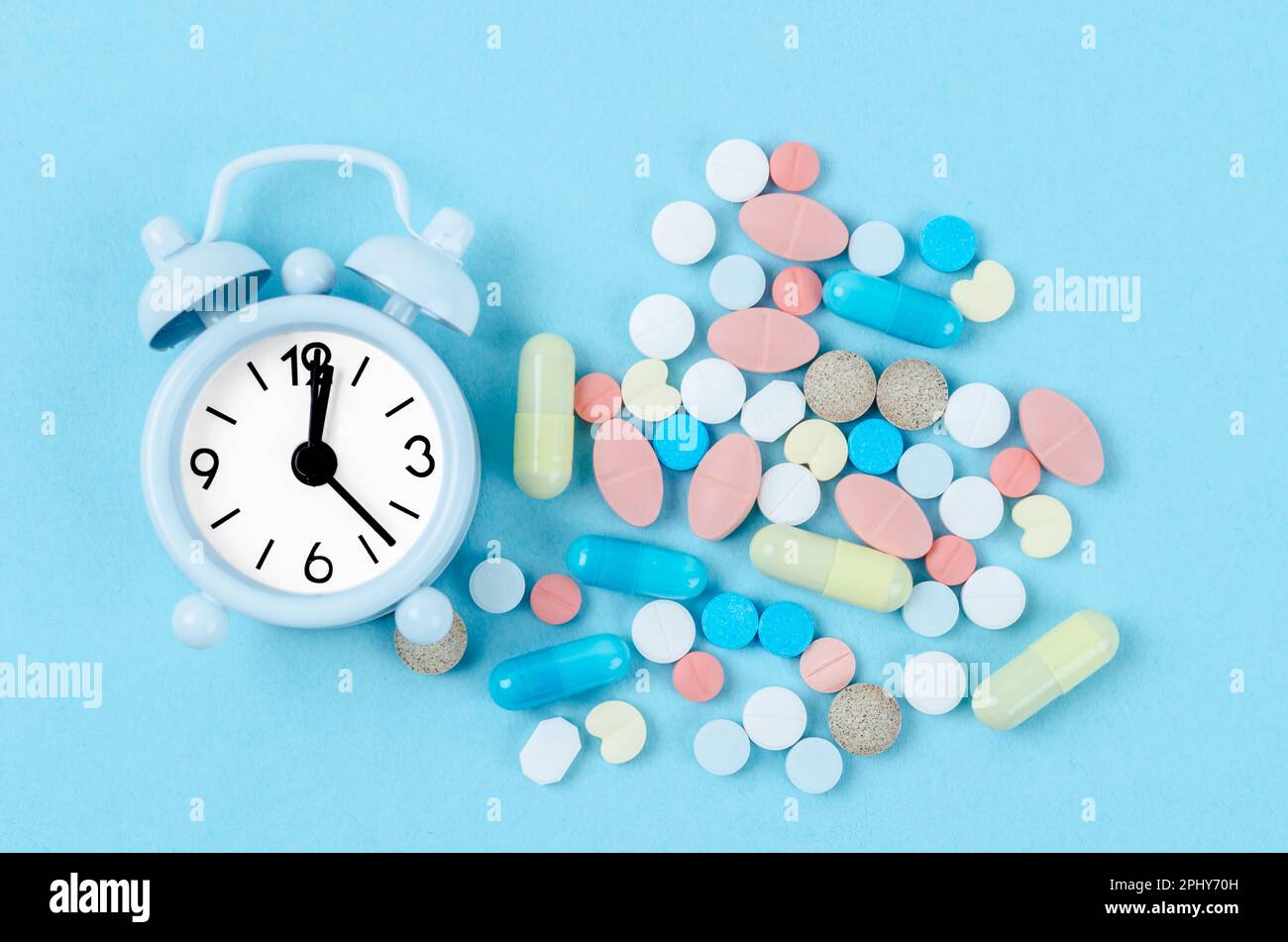 Pillen und Wecker auf blauem Hintergrund Stockfoto