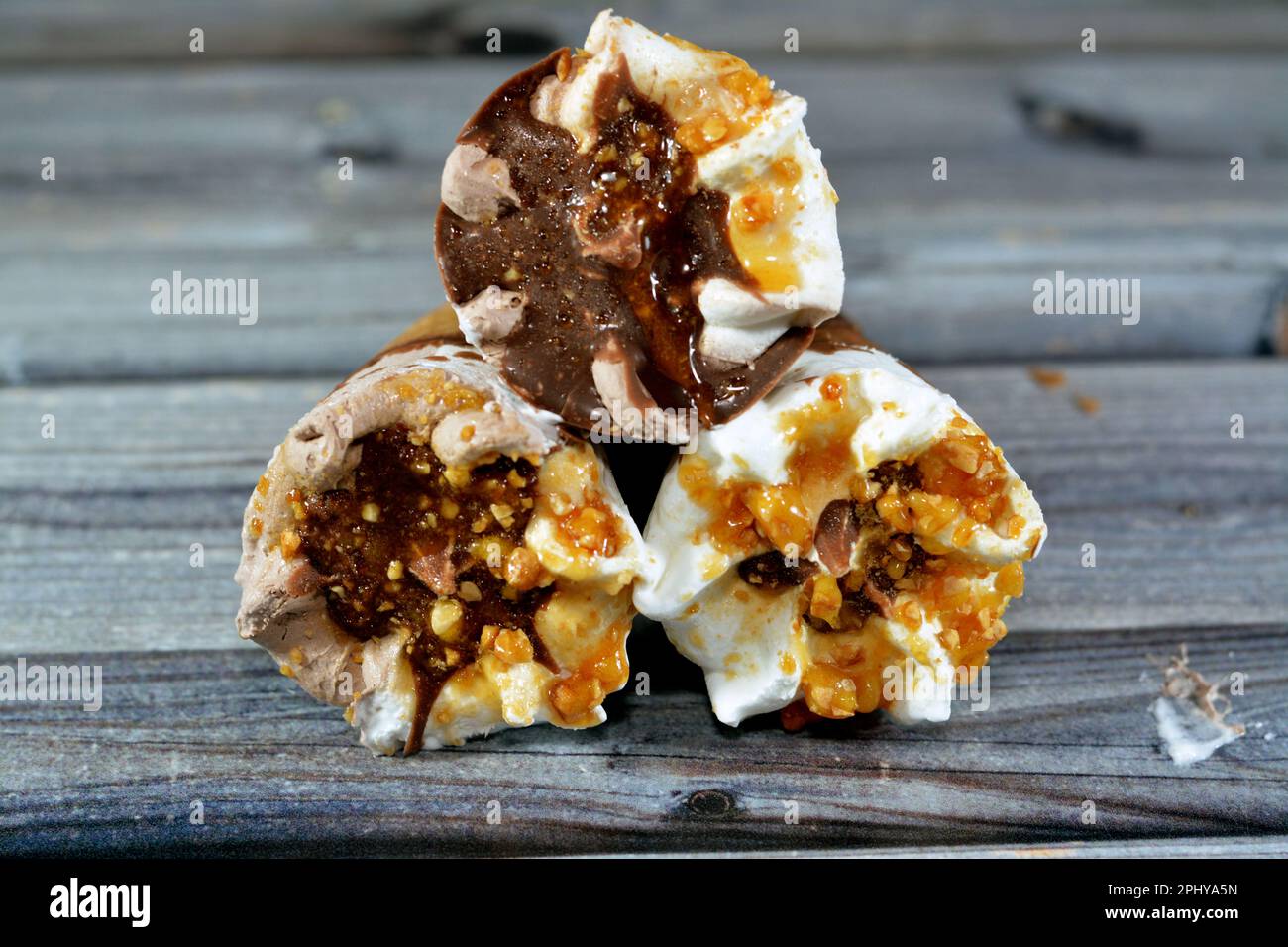 Eiscreme Vanille und Schokoladenzapfen mit Schokolade- und Karamellsoße und Nüssen in knusprigen Waffeln, Schmelzen von kaltem Eis in einem Stockfoto