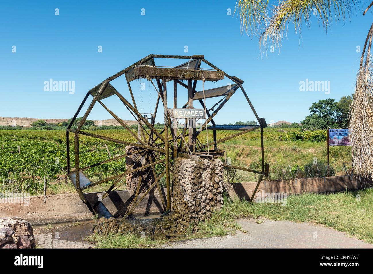 Keimoes, Südafrika - 25. Februar 2023: Bewässerungskanal, funktionierende Wasserradnachbildung und Weinberg in Keimoes in der Provinz Nordkap Stockfoto