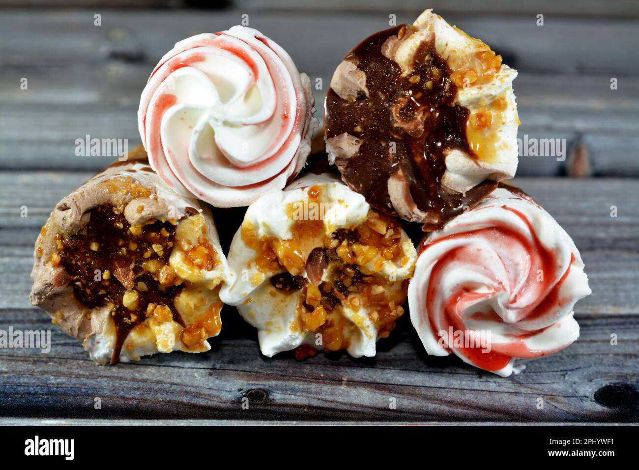 Eiscreme Vanille und Schokoladenzapfen mit Schokolade- und Karamellsoße und Nüssen in knusprigen Waffeln, Schmelzen von kaltem Eis in einem Stockfoto