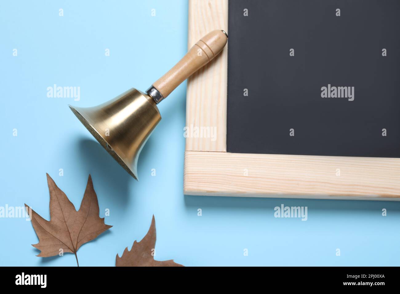 Goldene Schulglocke, Herbstblätter und Tafel auf hellblauem Hintergrund, flach liegend Stockfoto