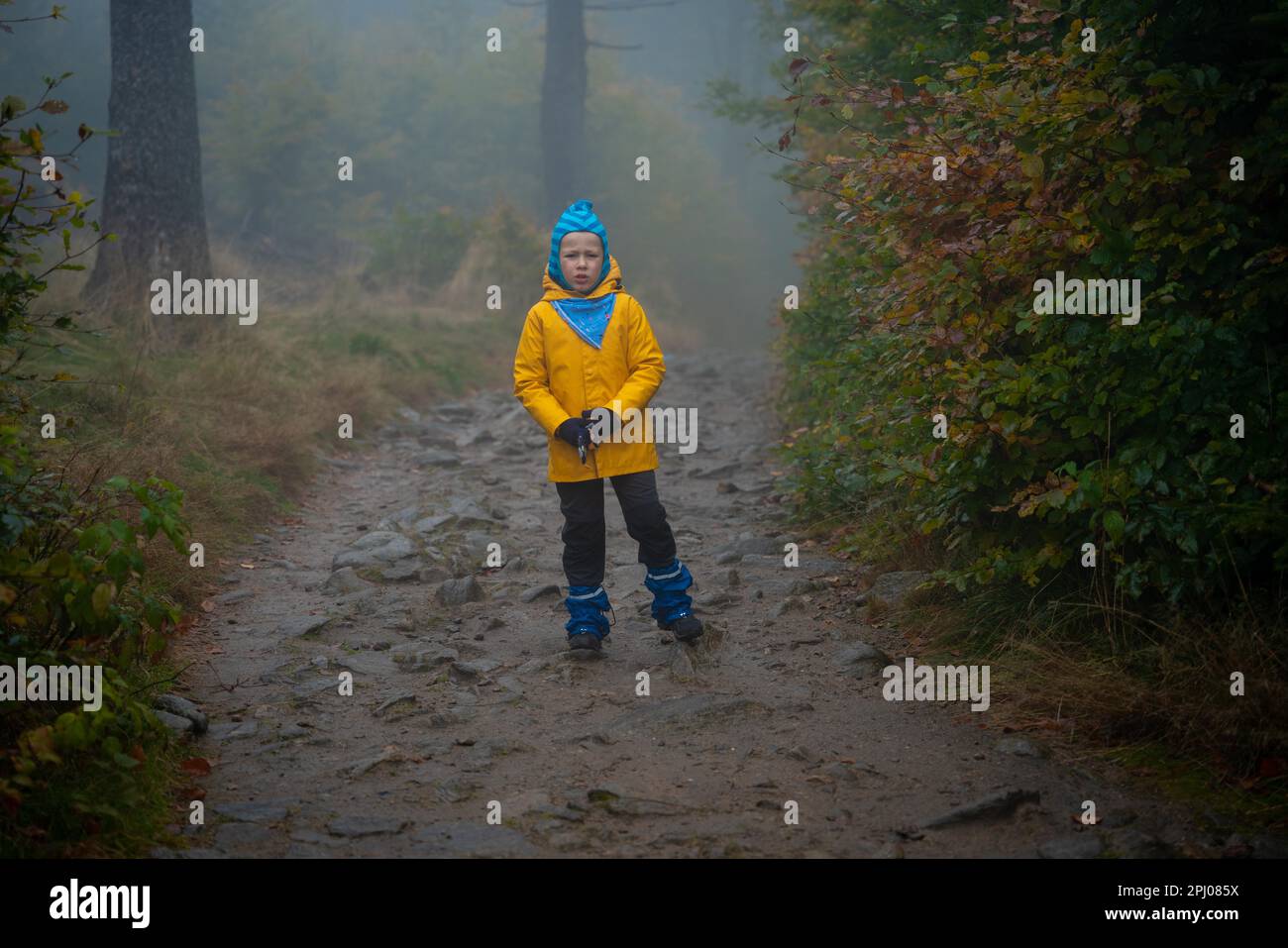 Das Kind steht im Regenmantel auf dem Bergpfad. Polnische Berge Stockfoto
