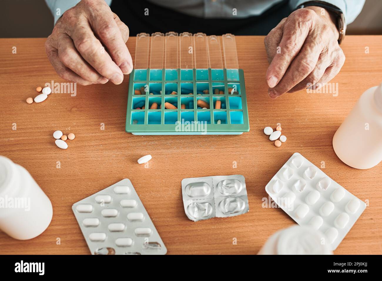Älterer Mann, der seine Medikamente in einen Pillenspender einsetzte. Älterer Mann nimmt Pillen aus der Schachtel. Gesundheitswesen und Alterskonzept mit Medikamenten. Medikamente Stockfoto