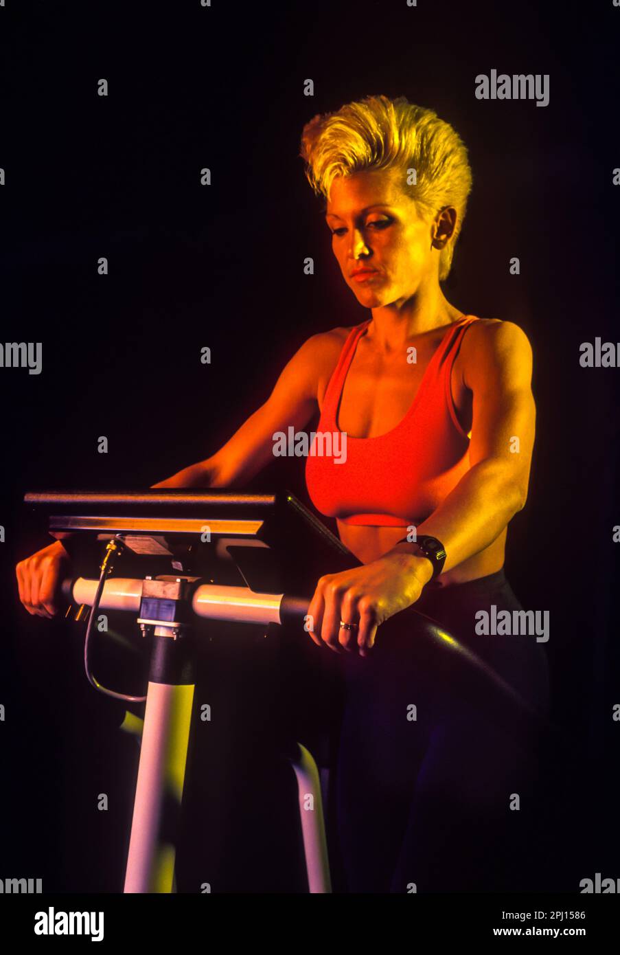 JUNGE FRAU AUF DEM TREPPENMEISTER-ÜBUNGSGERÄT Stockfoto