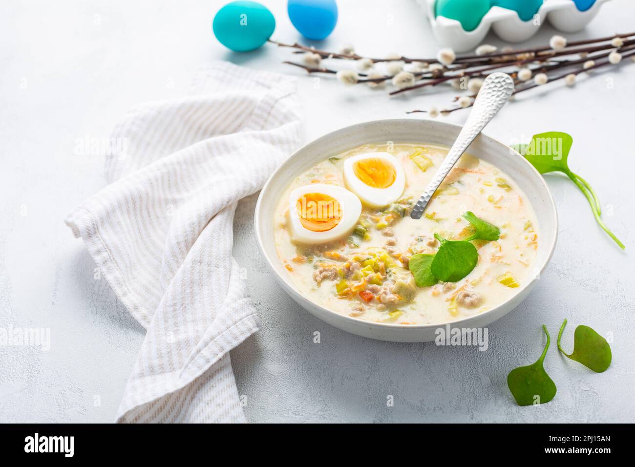 Traditionelle polnische Sauersuppe Zurek mit Rochenmehl, g und Gemüse auf dem Küchentisch mit Osterdekoration Stockfoto