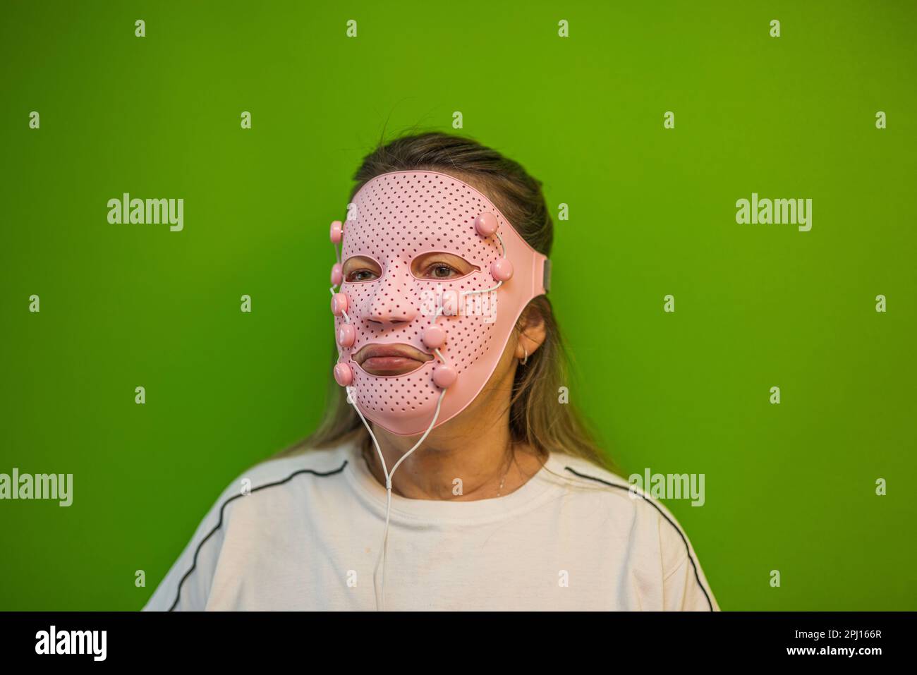 Nahaufnahme einer Frau mit pinkfarbener Gesichtsmaskenmaske auf Chroma Key-Hintergrund. Schweden. Stockfoto