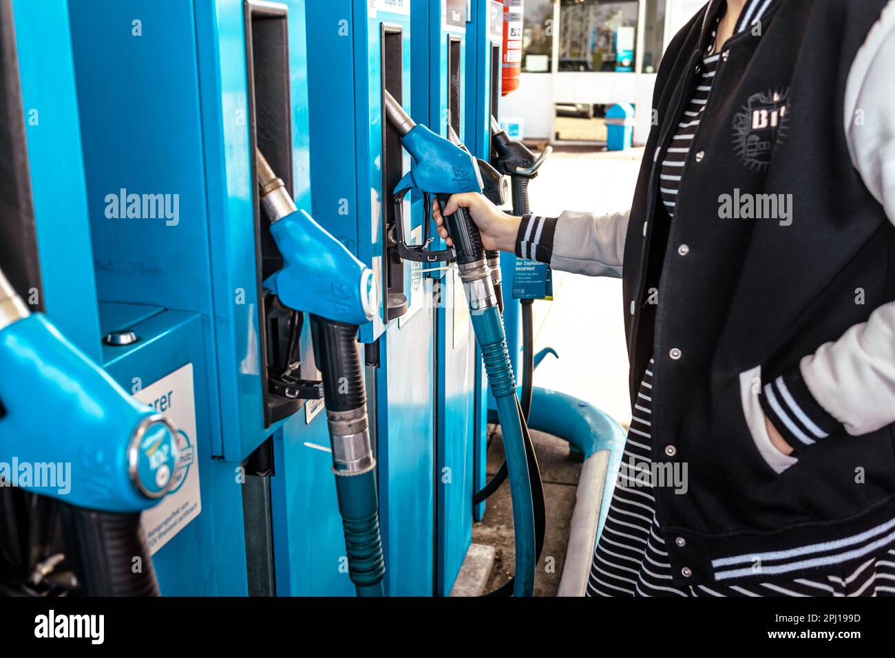 Hockenheim, Deutschland - 29. März 2023: Junge Frau betankt Auto an Selbstbedienungs-Tankstelle, Zapfsäulen Stockfoto