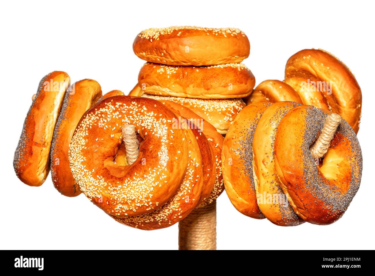 Schmackhafte Bagels werden mit Sesamsamen und Mohnsamen garniert, die auf einem Regal hängen. Isoliert auf weißem Hintergrund. Selektiver Fokus. Stockfoto
