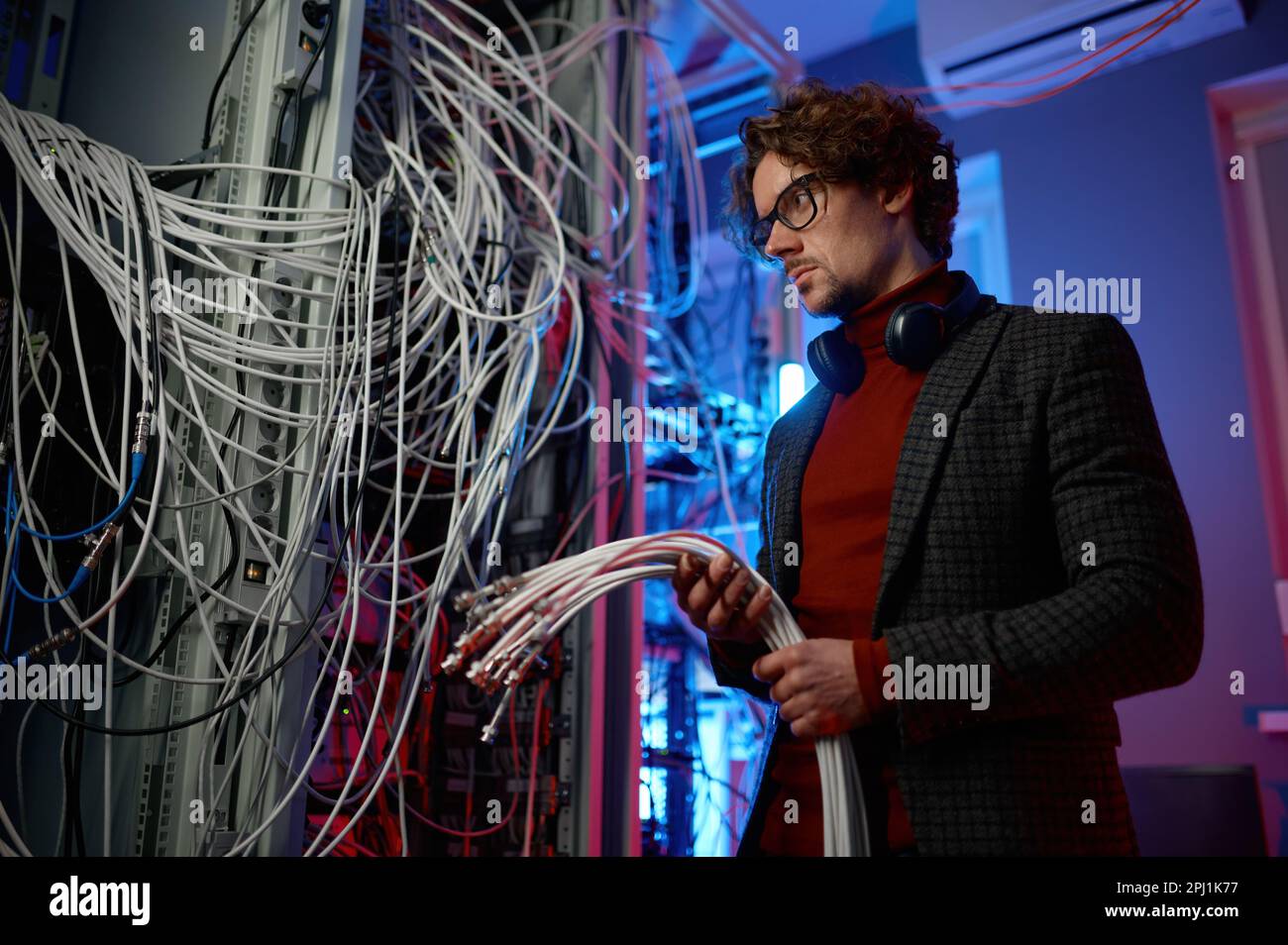 IT-Mann mit einem Haufen Kabel in den Händen im Serverraum Stockfoto