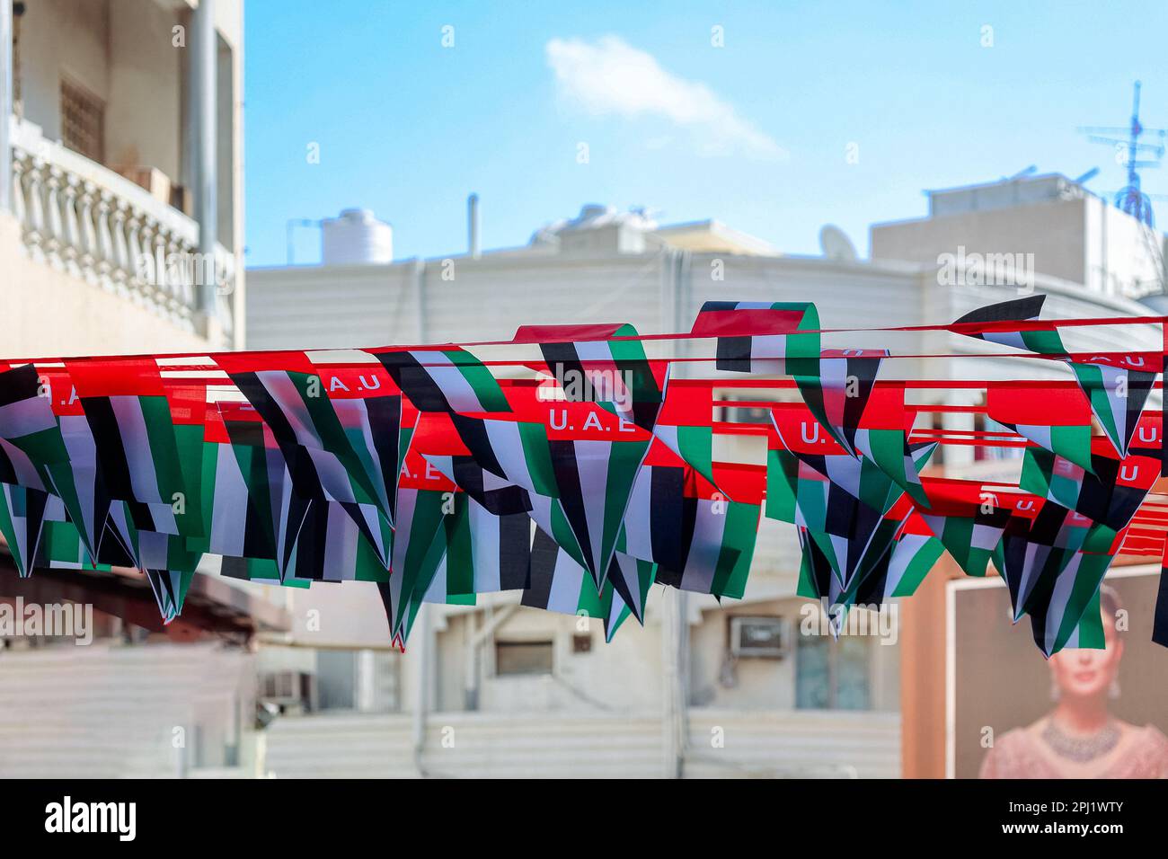 Hängende Dekorationen von vielen Nationalflaggen der Vereinigten Arabischen Emirate auf der Straße von Dubai. Natoinal Day VAE. Fahnen in Reihen winken im Wind gegen den blauen Himmel. Hochwertige Fotos Stockfoto