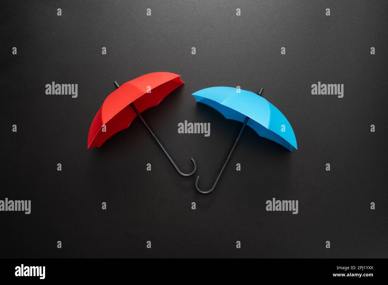 Rote und blaue Regenschirme isoliert auf schwarzem Hintergrund Stockfoto