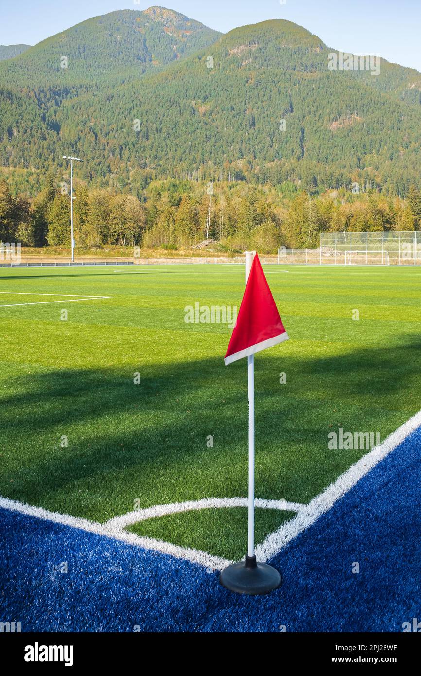 Fußballfeld. Foto eines Sportplatzes mit grünem synthetischem Gras und weißer Linie. Detail der Ecke mit roter Flagge. Niemand, selektiver Fokus, Straßenpho Stockfoto