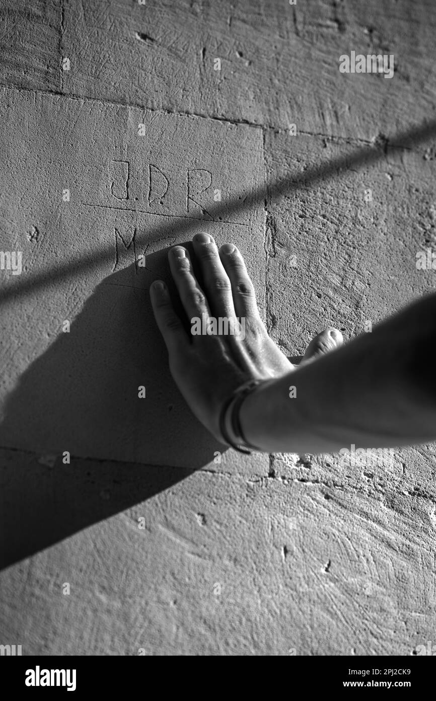 Eine Person, die eine Steinmauer mit Buchstaben berührt Stockfoto