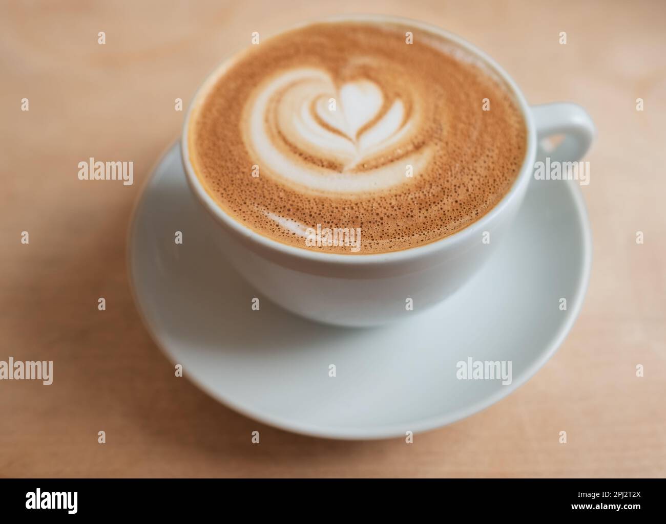 Guten Morgen Kaffee. Cappuccino mit Latte Art auf Holzhintergrund. Wunderschöner Schaum, Kaffeetasse auf einem rustikalen Tisch, gemütliches Frühstück, Vintage-Stil Stockfoto
