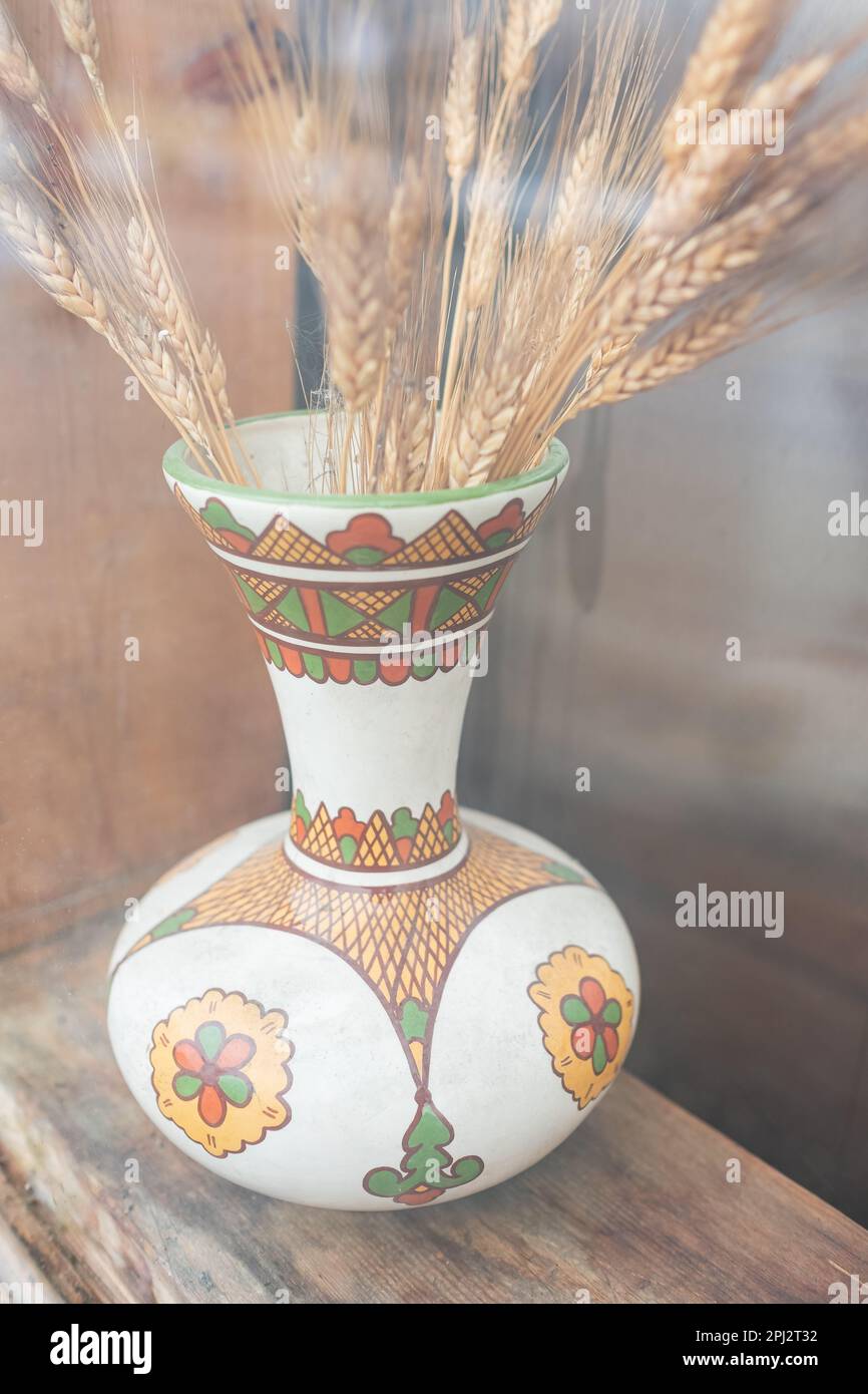 Getrocknete Weizenohren in Vintage-Vase auf Holzhintergrund. Herbst, Herbst, Thanksgiving-Tag-Konzept. Kopier-Weltraumspikelets aus Weizen in Keramikvase Stockfoto