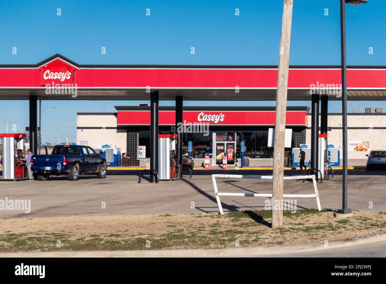 Ein männlicher Kunde pumpt Benzin in Casey's General Store, während ein anderer in Blackwell, Oklahoma, USA, spaziert. Stockfoto