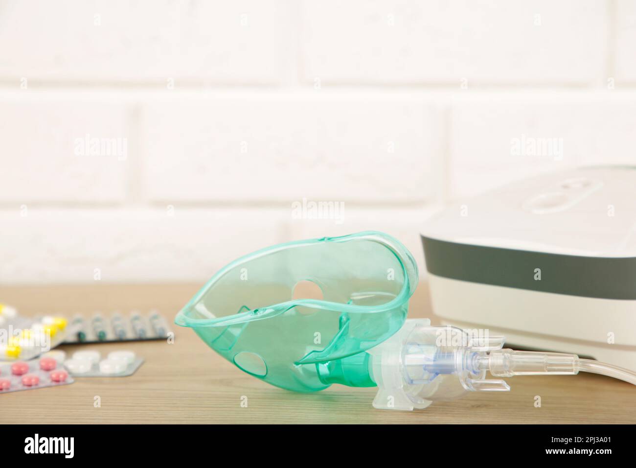 Kompressor-Vernebler mit Maske und Pillen auf dem Tisch mit Kopierplatz. Stockfoto