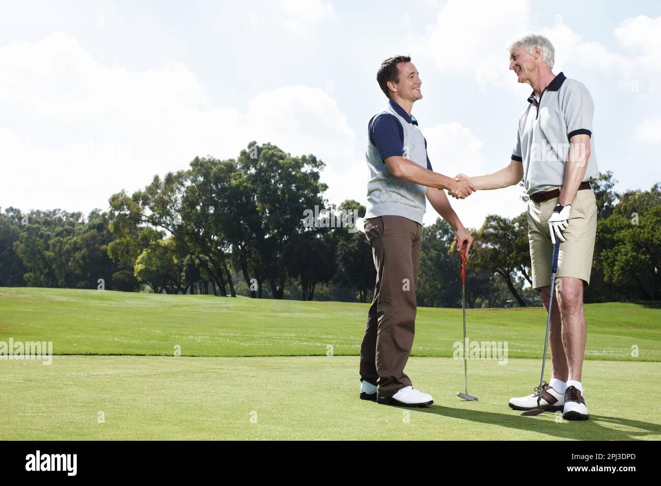 Wir müssen bald wieder zusammen spielen. Zwei Männer, die sich nach einer befriedigenden Runde Golf die Hand schütteln. Stockfoto