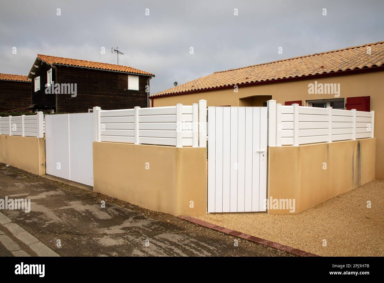 Zeitgenössischer weißer Vinylzaun um den Garten herum schützt das Haus mit Türportal Stockfoto